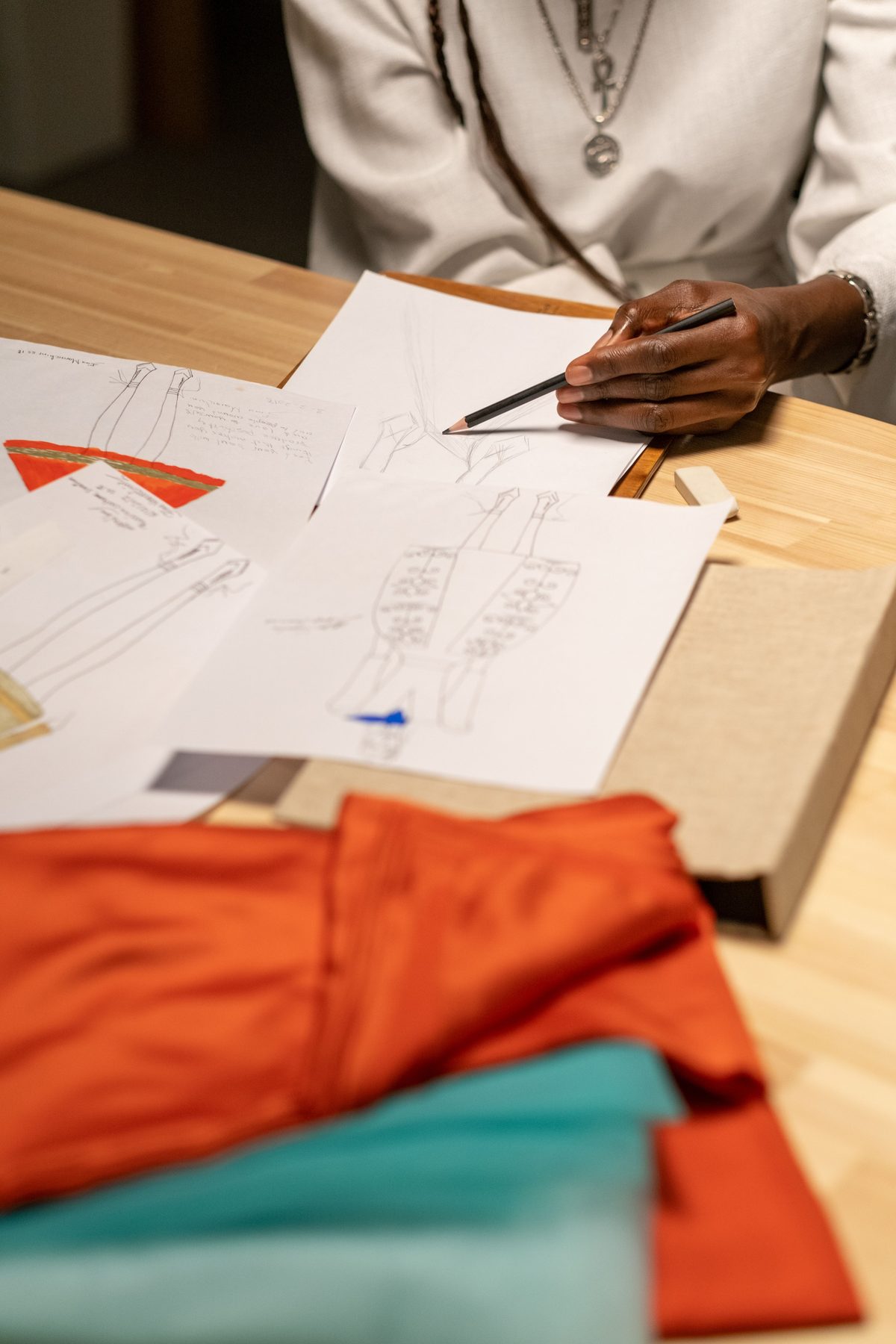 Designer working on tech-pack sketches with fabric